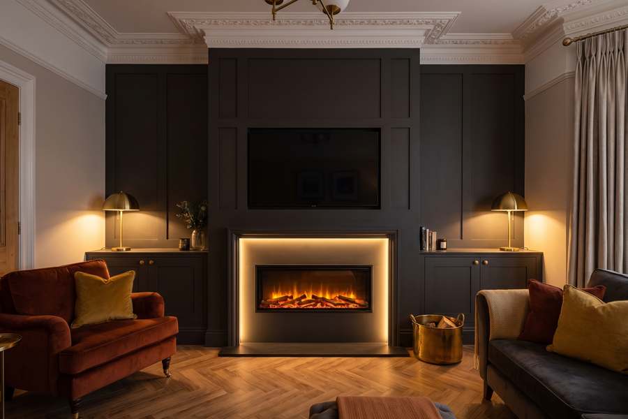 A panelled media wall in a dark warm finish with a linear inset electric fire and a screen recessed above it